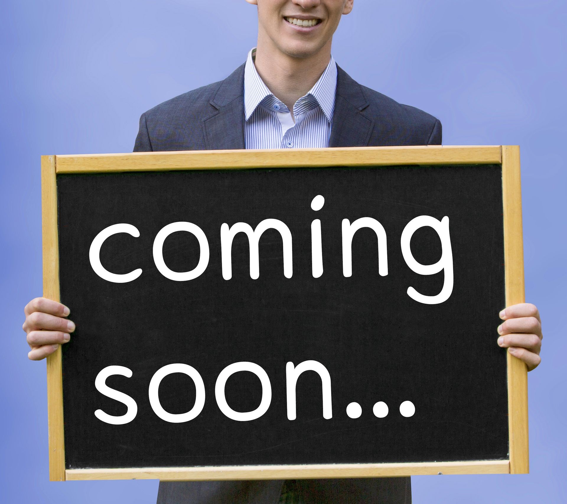 young businessman holding chalkboard with the words Coming Soon